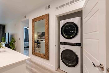 a small laundry room with a washer and dryer and a large mirror
